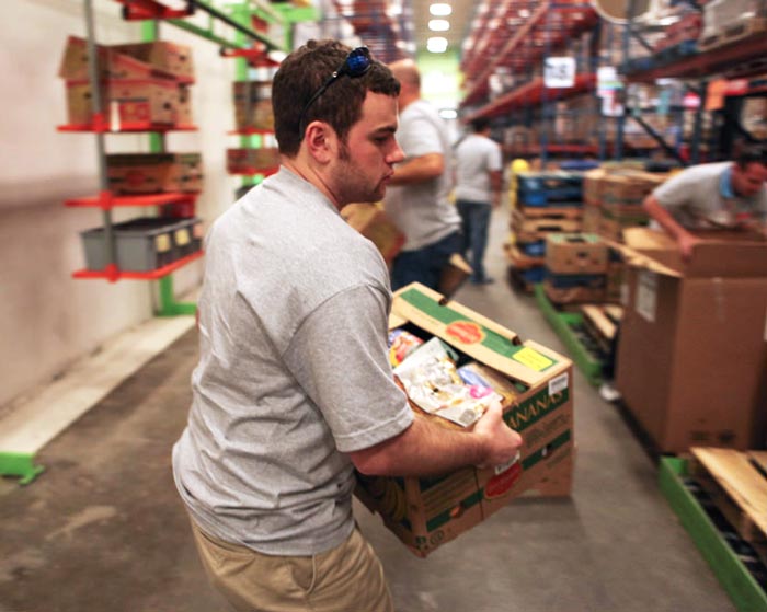 Warehouse worker moving boxes of food in a commercial food bank
