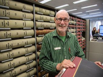 Photo of employee with stacks of books behind him