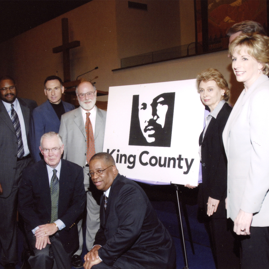 Group of people gathered around a logo of Martin Luther King