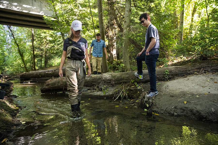 Three researchers stand in Longfellow creek