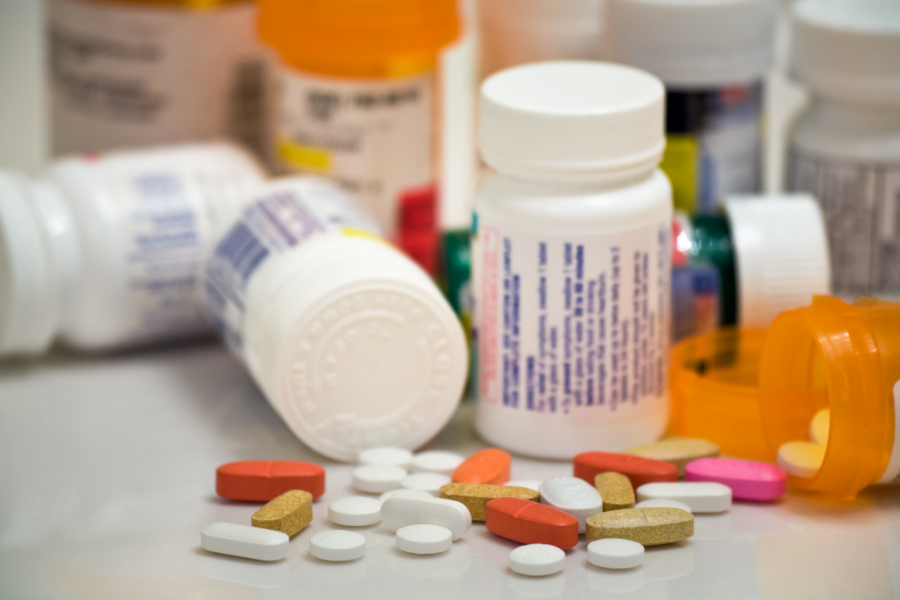A collection of medication bottles with a variety of pills spilled out from one opened container.