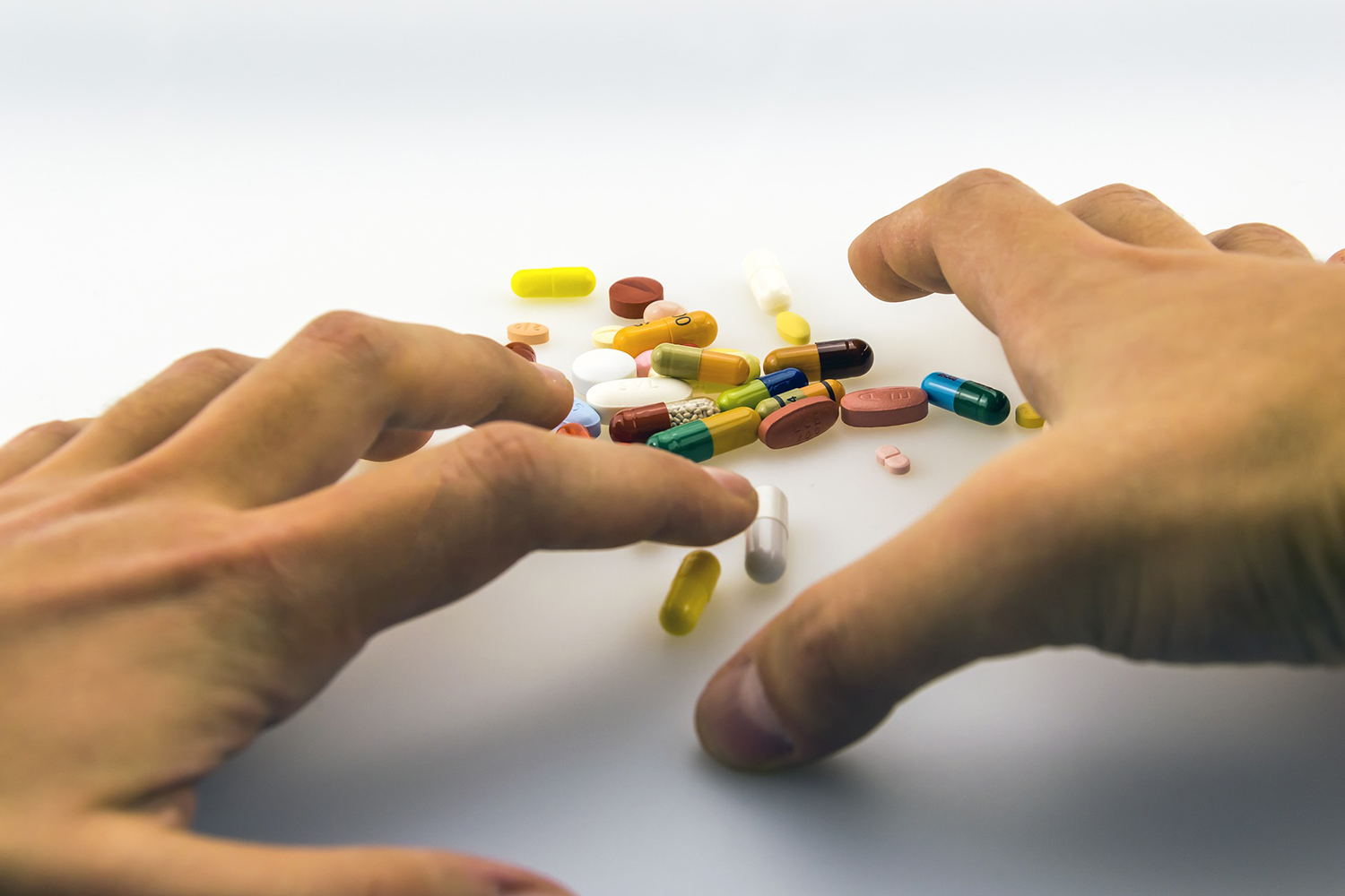 Hands reaching for a pile of medicines