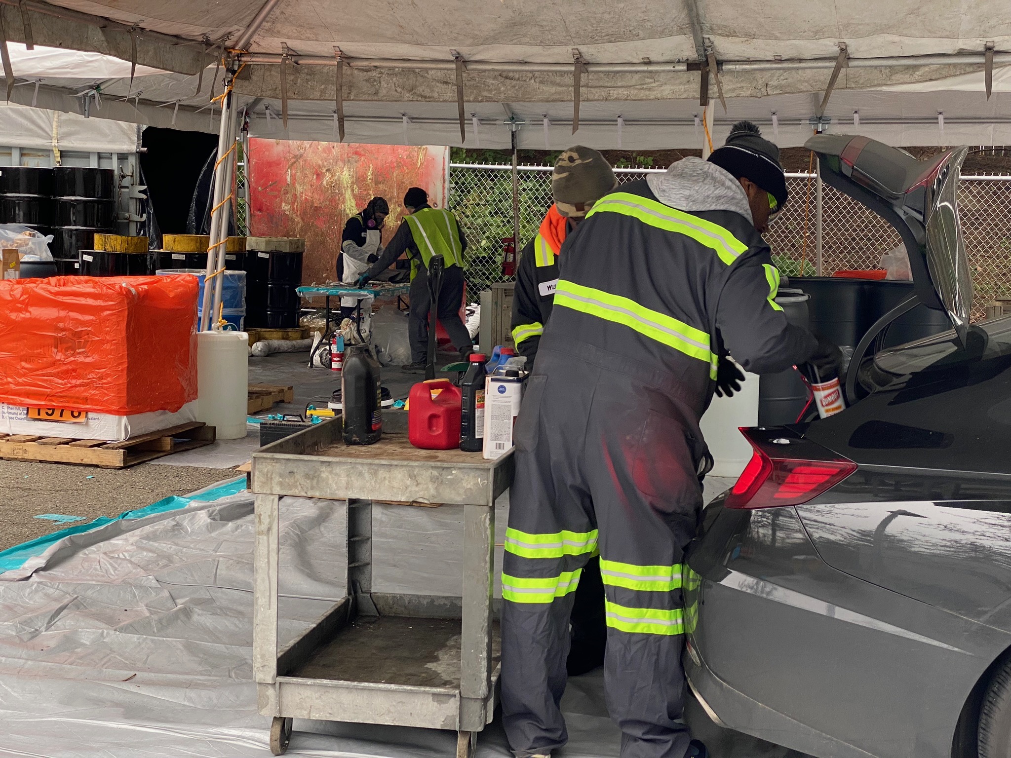 Workers unload household hazardous waste products from the trunk of a car at a Wastemobile site.