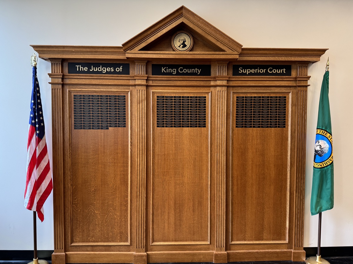 Wooden plaque listing the names of King County Superior Court Judges with American (left) and Washington State (right) flags on either side of the structure