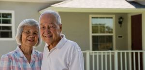 Senior couple smiling in front of house