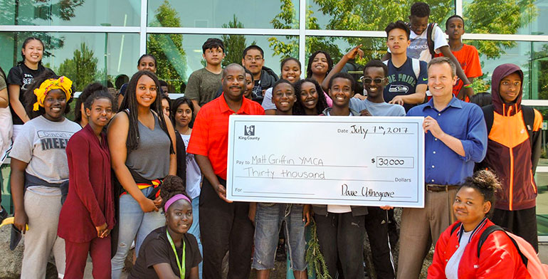 Councilmember Upthegrove posing with check and group of YMCA youth.