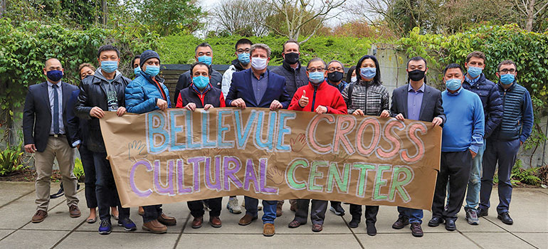Group holding a sign with hand lettering "Bellevue Cross Cultural Center".