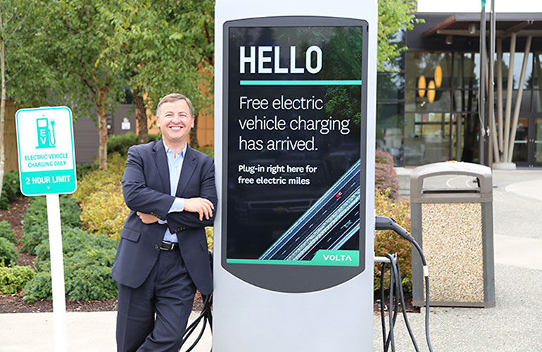 Councilmember Dembowski leans against a charging station. Text on the station's screen reads - Hello, free electric vehicle charging has arrived.