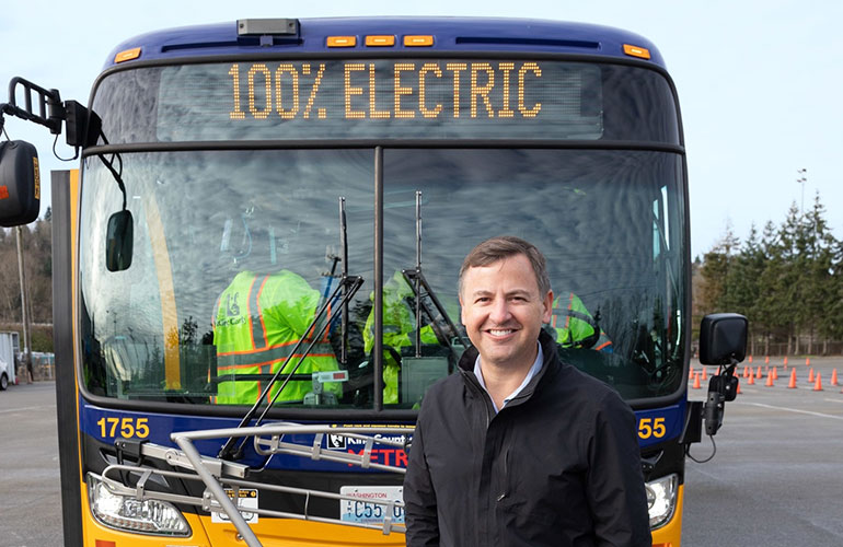 Councilmember Dembowski standing in front of an electric Metro bus.