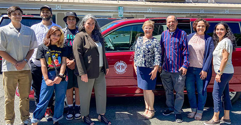Councilmember Perry poses with van recipients in front of a red van.
