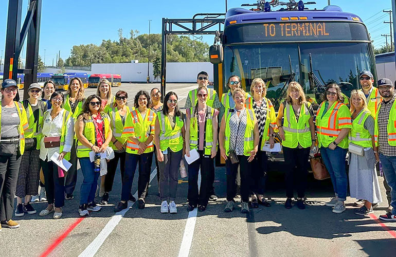 Large group wearing safety vests in front of a Metro bus.