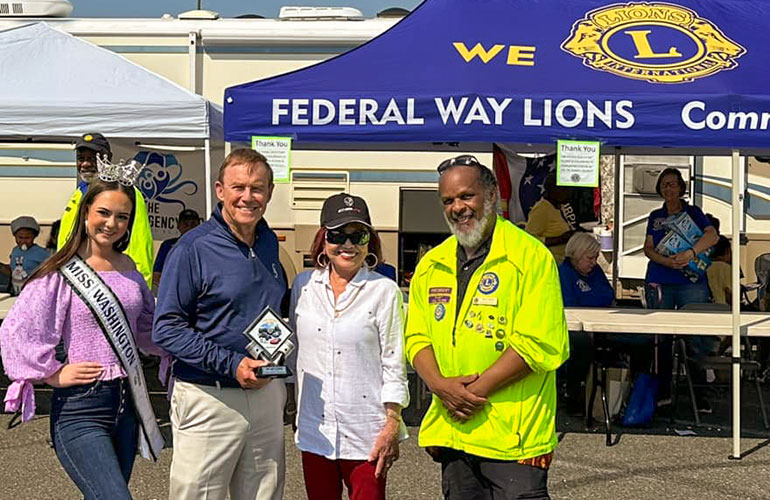Miss Washington, Councilmember von Reichbauer and others pose in front of the Federal Way Lions booth.