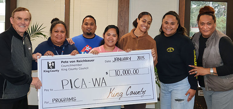 Group holding large check for ten thousand dollars.