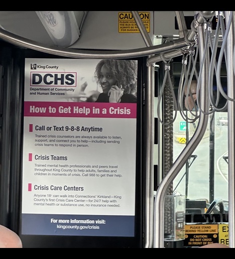 Image of the interior of a King County Metro bus showing an advertisement for how to access help in a crisis.