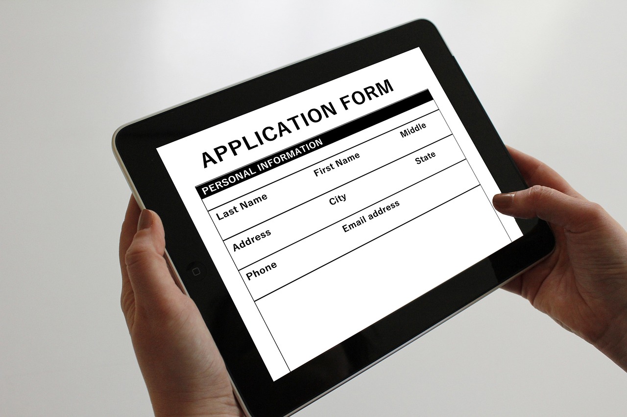 picture of hands holding a tablet and filling in an online job application form