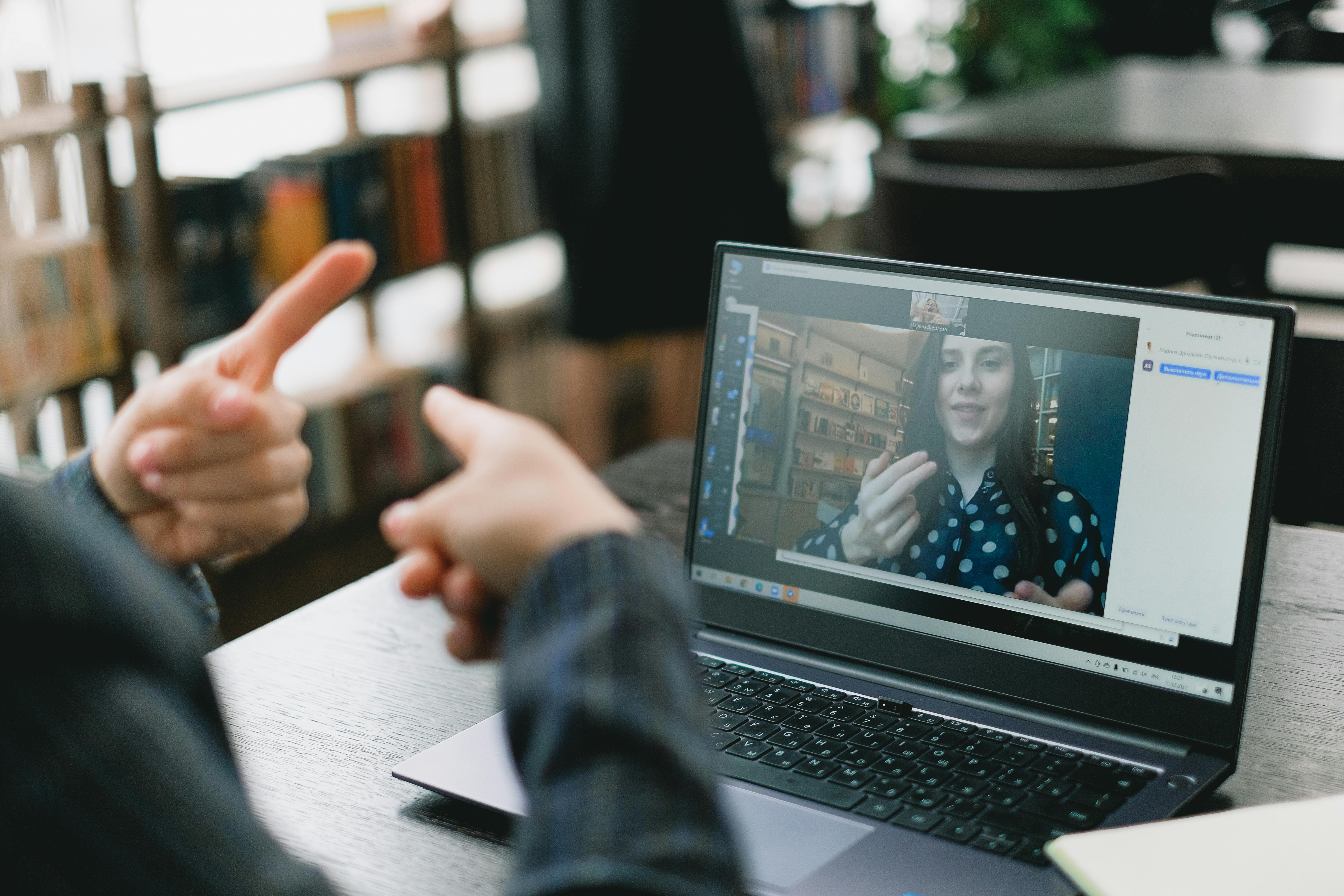 a person in a virtual meeting who is using sign language to communicate.