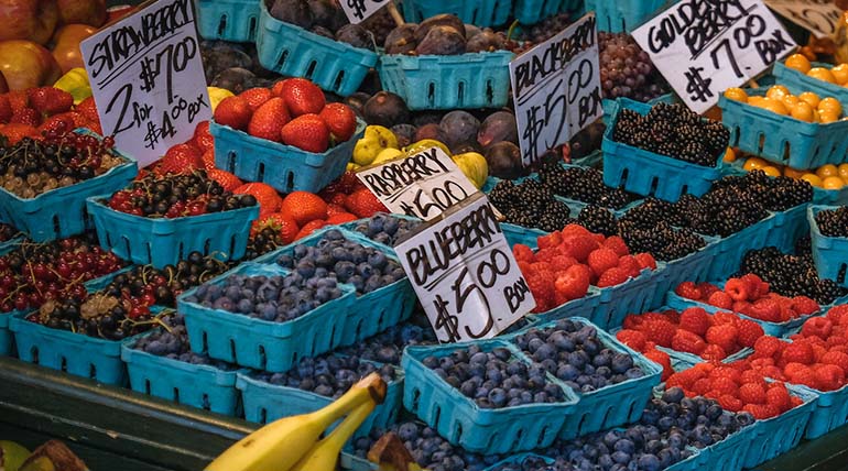 Farmers market display with local berries including strawberries, raspberries, blueberries and boysenberries