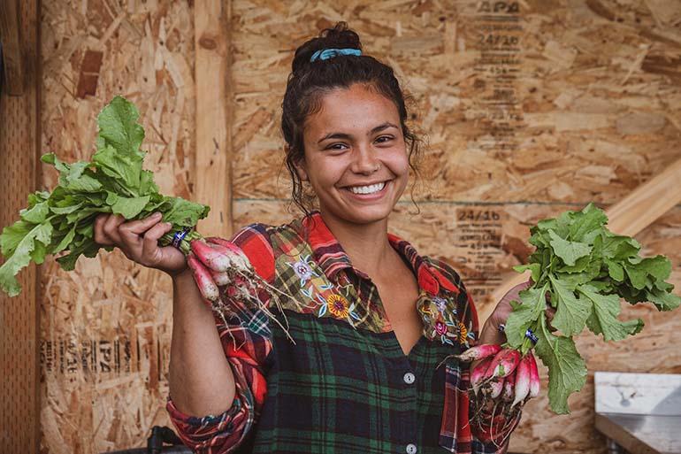 Woman shows off fresh radishes on a farmland tour