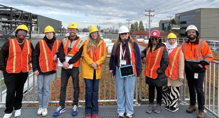King County project manager with seven people representing community-based organizations. The group has orange vests and hard hats as they pose for a photo at the Georgetown Wet Weather Treatment Station.