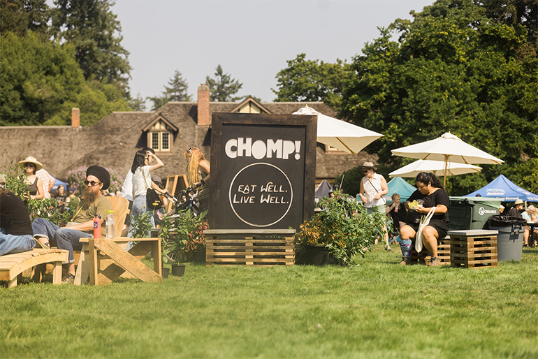 People sitting outside Marymoor Parks Clise Mansion enjoying good food near a sign for Chomp! Eat well. Live well.