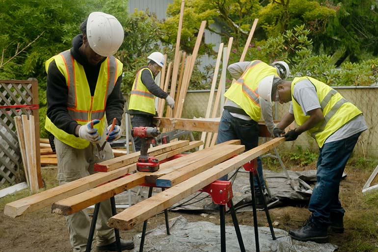 Workers recovering good lumber from a demolished house
