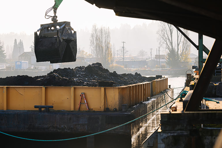 Removing polluted sediment from a barge for processing and disposal