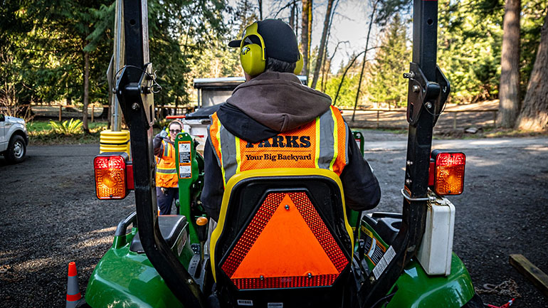 Parks staff driving a tractor mower