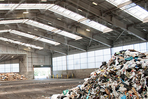 Transfer station enclosure with pile of garbage and misters spraying enzymes to control odors