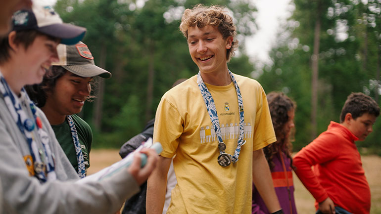 Smiling camp counselor leads a group activity with the kids