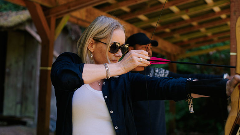 Executive Shannon Braddock takes aim with a bow and arrow at the archery range