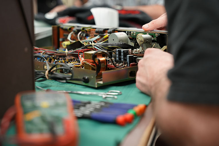 Electronics technician working on an Akai receiver - amplifier