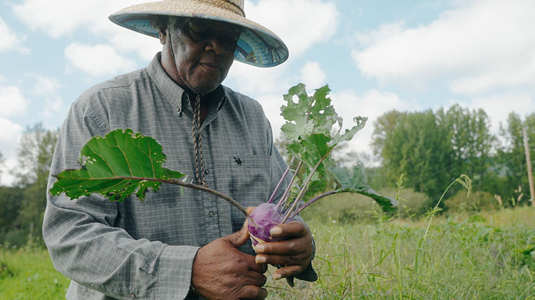 Man holding a kohlrabi root vegetable