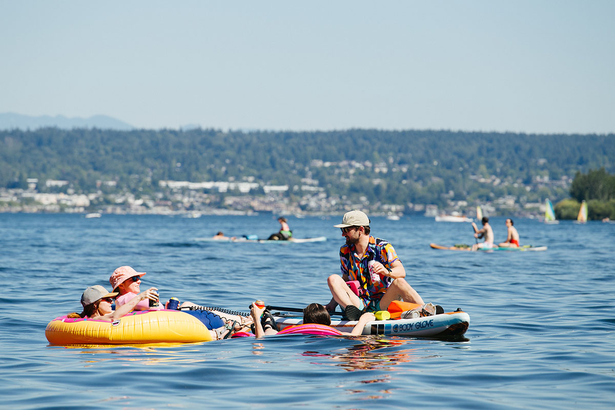Swimmers on floaties on Lake Washington on a warm, blue sky day