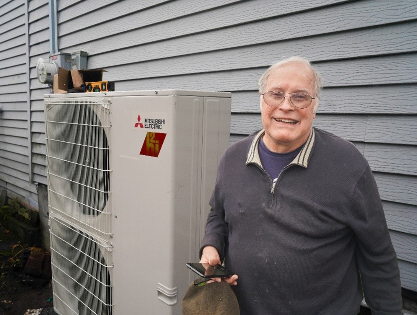 man smiling in front of heat pump