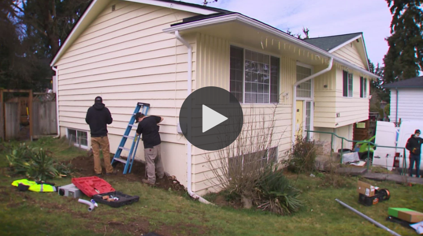 contractors hold a ladder against a home