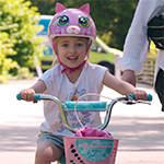 Young bicyclist with a pink kitty helmet riding on the Lake to Sound Trail