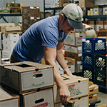 Farmstand Local Foods worker organizing boxes of produce
