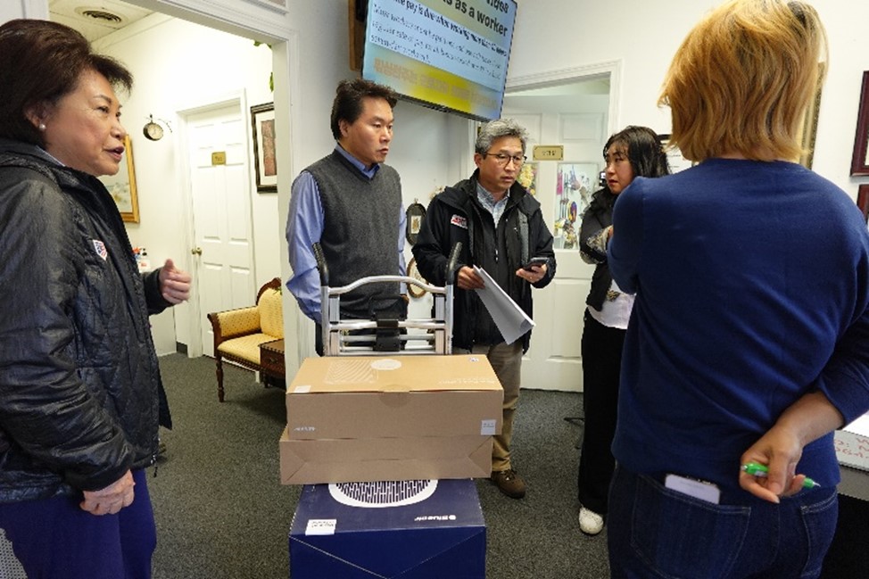 people stand around a dolly with an air purifier on it 