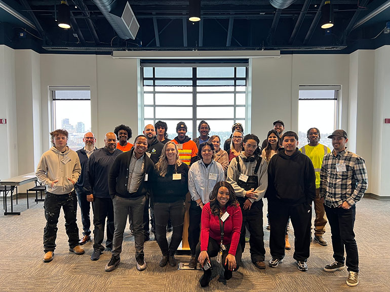 large group of people smiles and poses for a photo at a hiring luncheon