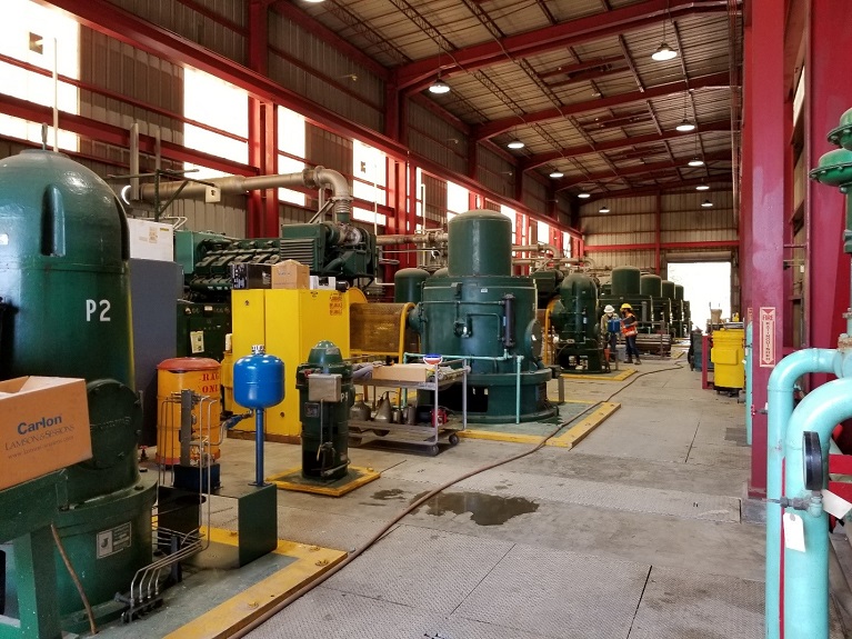 The inside of a mechanical building with green and yellow machinery.