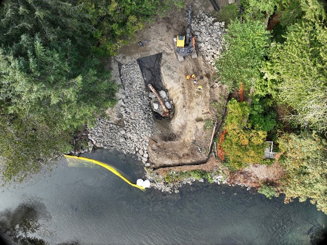 Aerial image looking down at a revetment being built with rocks and logs.