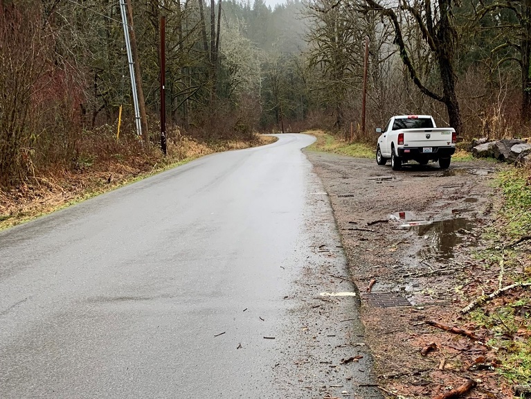 Tolt River Road Northeast wet from rainfall with mud and a white truck on the shoulder.