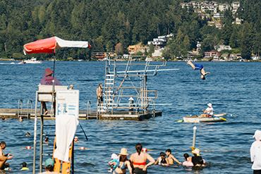 People enjoying a swimming beach with a floating diving platform in Lake Washington.
