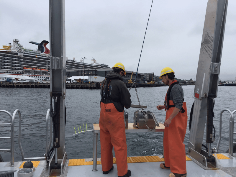 Photograph of two environmental scientists sampling marine sediments.