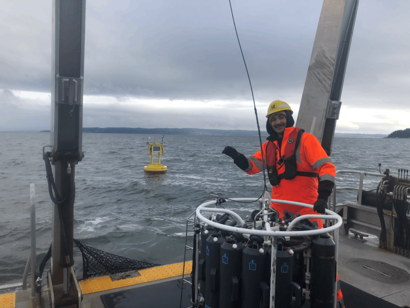 A marine scientist on a research vessel with a marine mooring in the background.