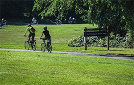 Couple riding bikes on Sammamish River Trail surrounded by grassy fields and trees