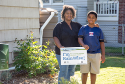 Mother and son on their lawn in front of a sign that says I am RainWise.