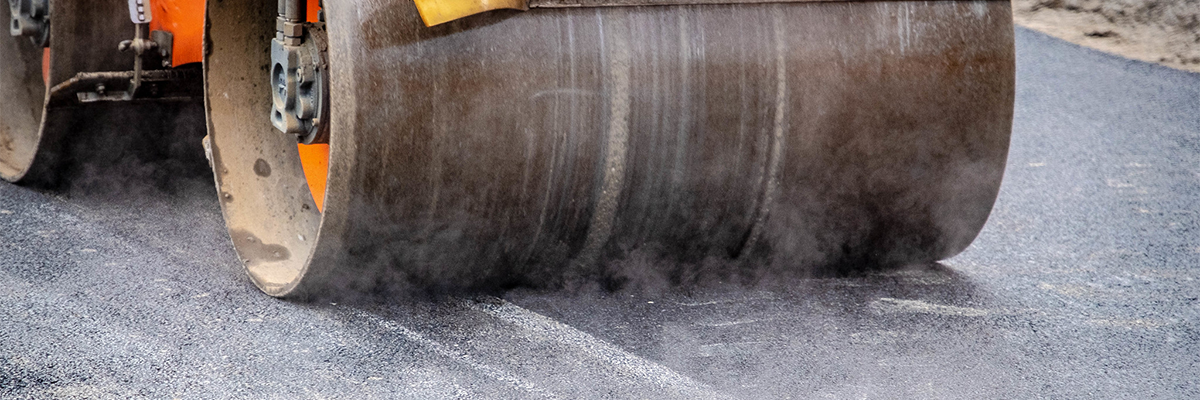 Close up of a steam roller smoothing fresh asphalt