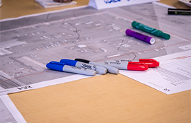 Some designs lay on a table with multi-colored pens