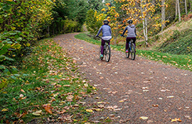 Two cyclists ride down the Green to Cedar Rivers Trail